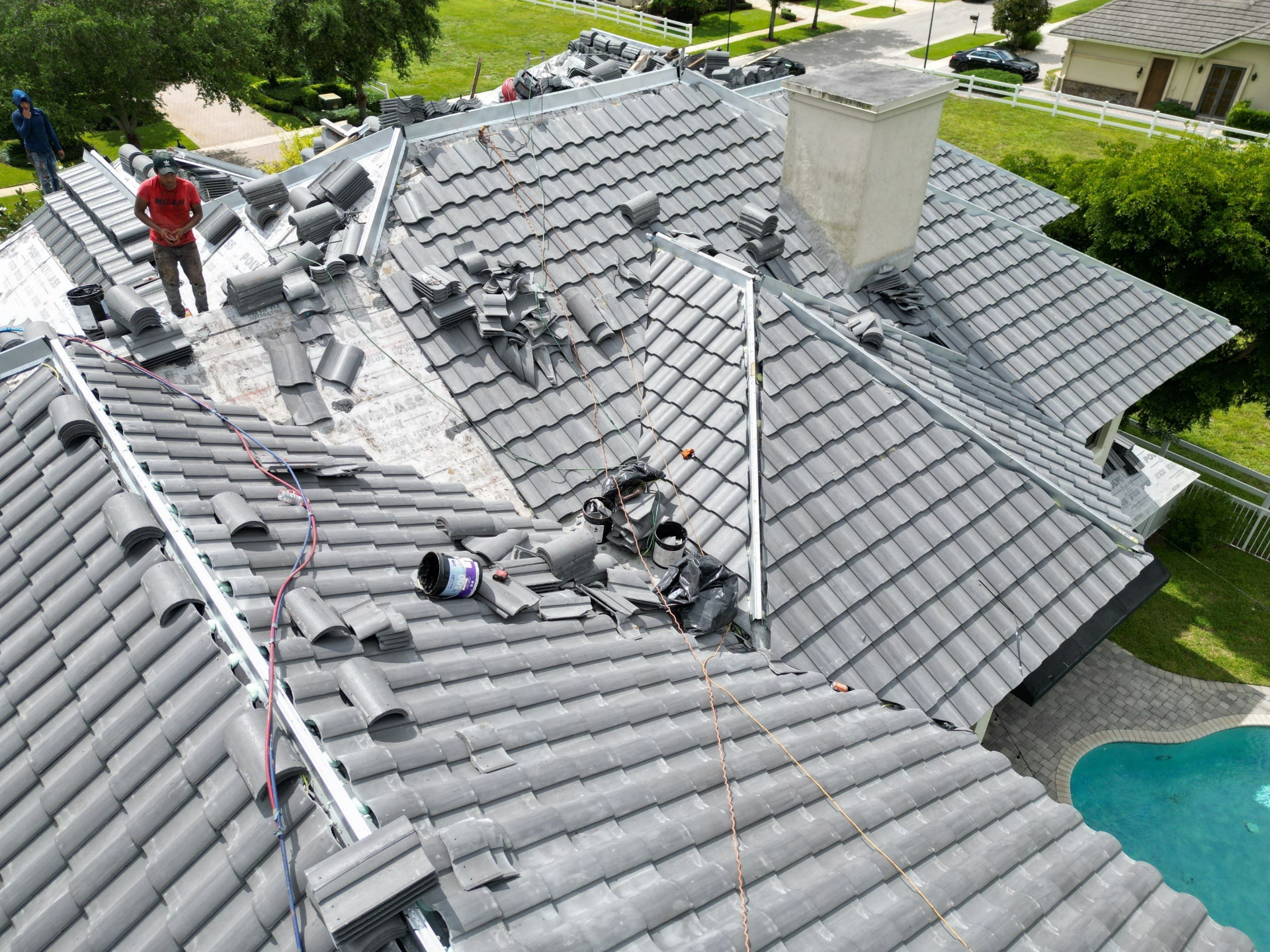 Roofing crew installing flat concrete tile with new underlayment and metal flashing