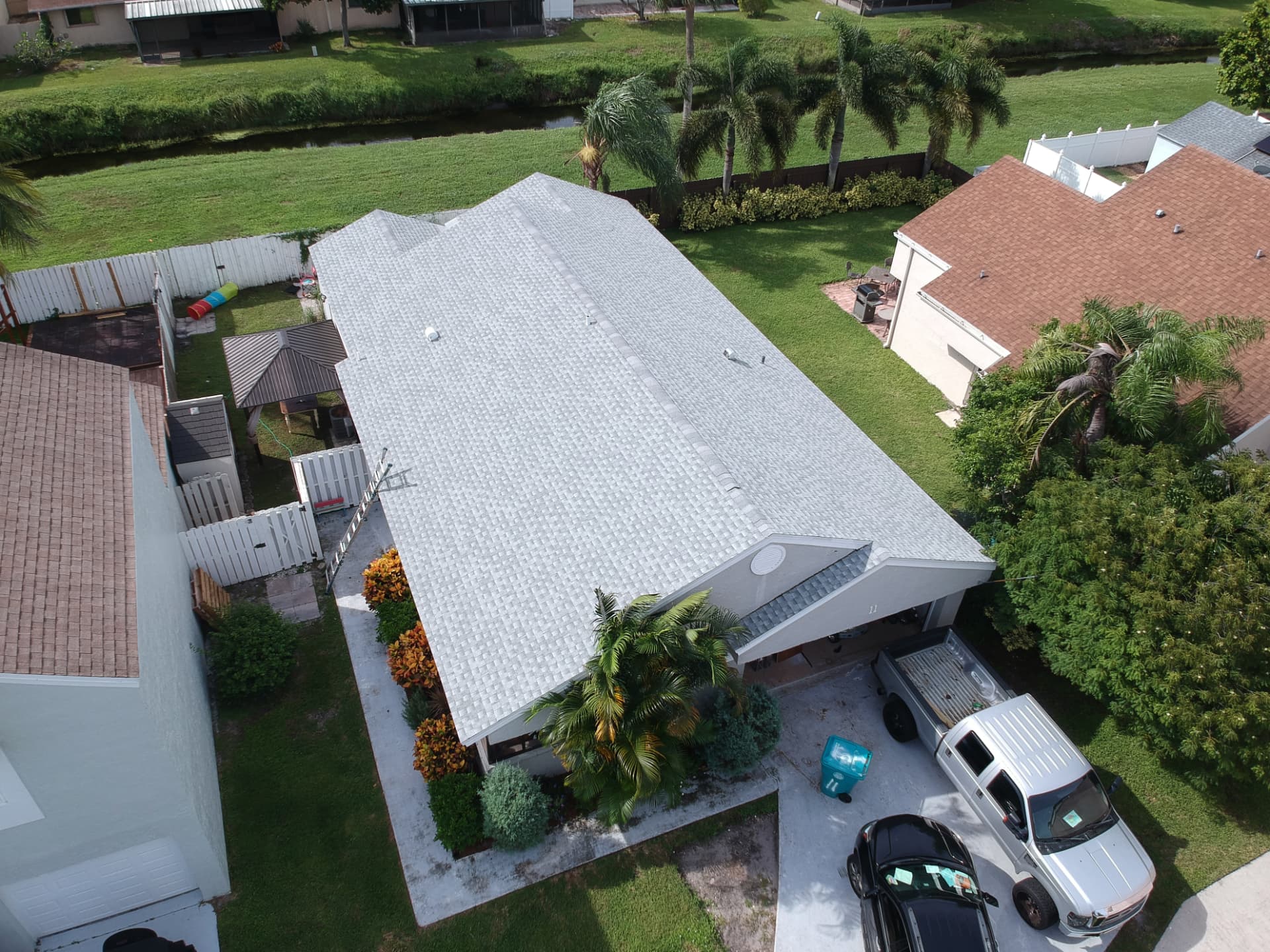Aerial view of a completed light-gray architectural shingle roof on a single-family South Florida home